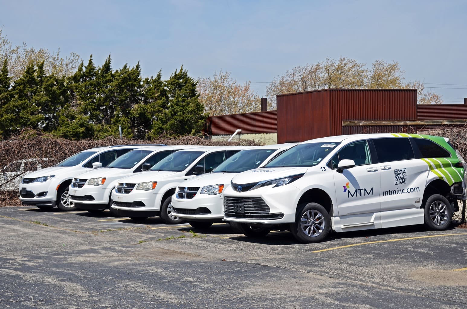 Wheelchair-accessible mobility van with lowered floor and ramp deployed, parked outside by Access Mobility Vans.