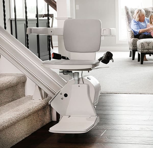 Stair lift installed on a residential staircase with a sleek rail and foldable seat by Access Elevator, Inc.