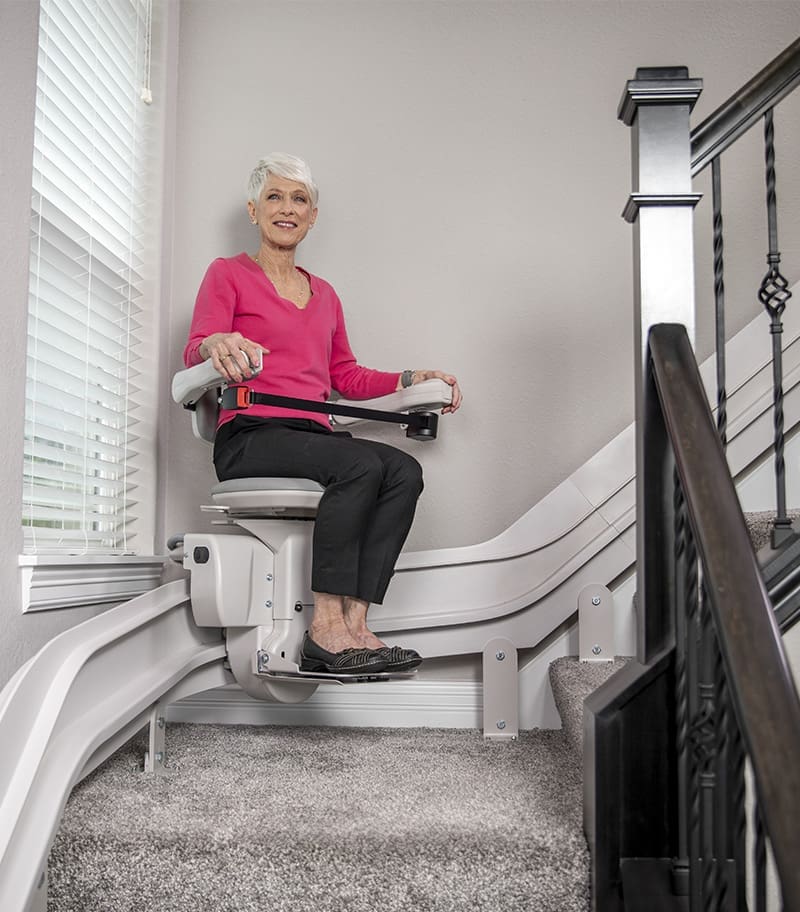 Bruno Elite Curved Stair Lift at Center of Rail at Curve with Rider Looking Up and To the Right Into the Camera