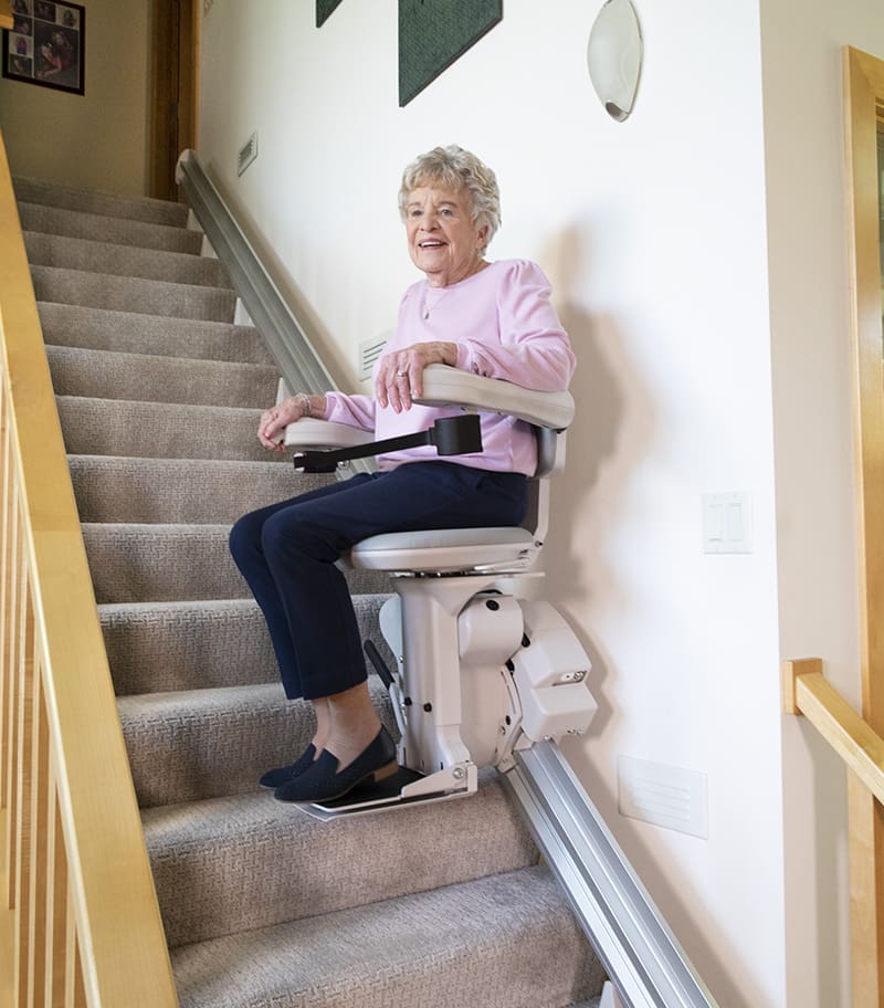 Happy Lady Riding Down the Stairs in her Home on Bruno Elite Bariatric Straight Stair Lift.