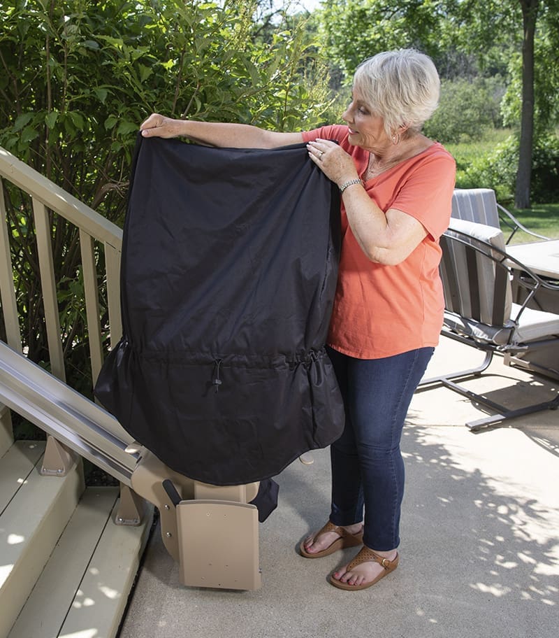 Owner Placing Rain and Snow Cover over Bruno Elite Outdoor Bariatric Stair Lift to Protect Lift from Elements