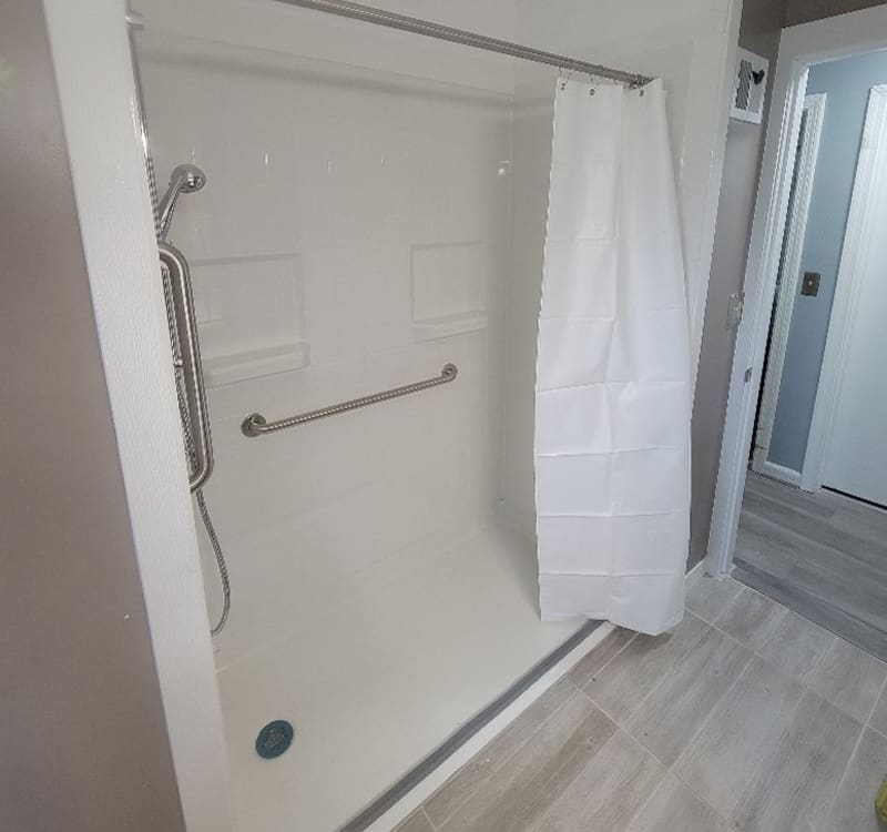 Modern accessible bathroom featuring grab bars, a roll-in shower, and wheelchair-friendly layout by Access Elevator, Inc.