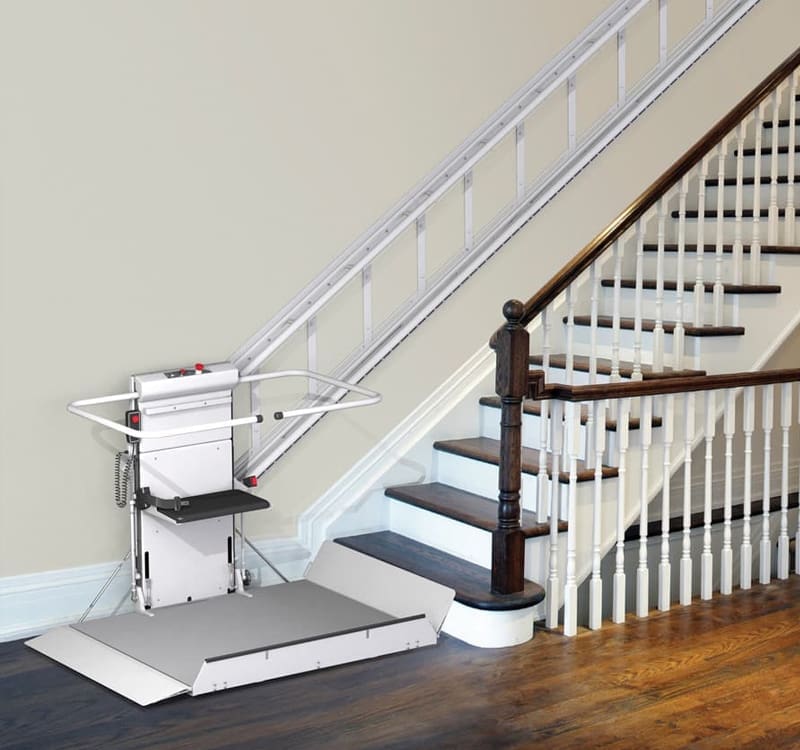 Inclined platform lift installed along a staircase with a foldable platform and safety rails by Access Elevator, Inc.