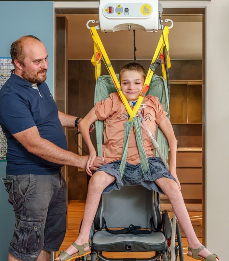 Access-Surehands-Portable-Ceiling-Lift-System-03 Father assisting disabled son with transfer by using a portable ceiling lift from SureHands