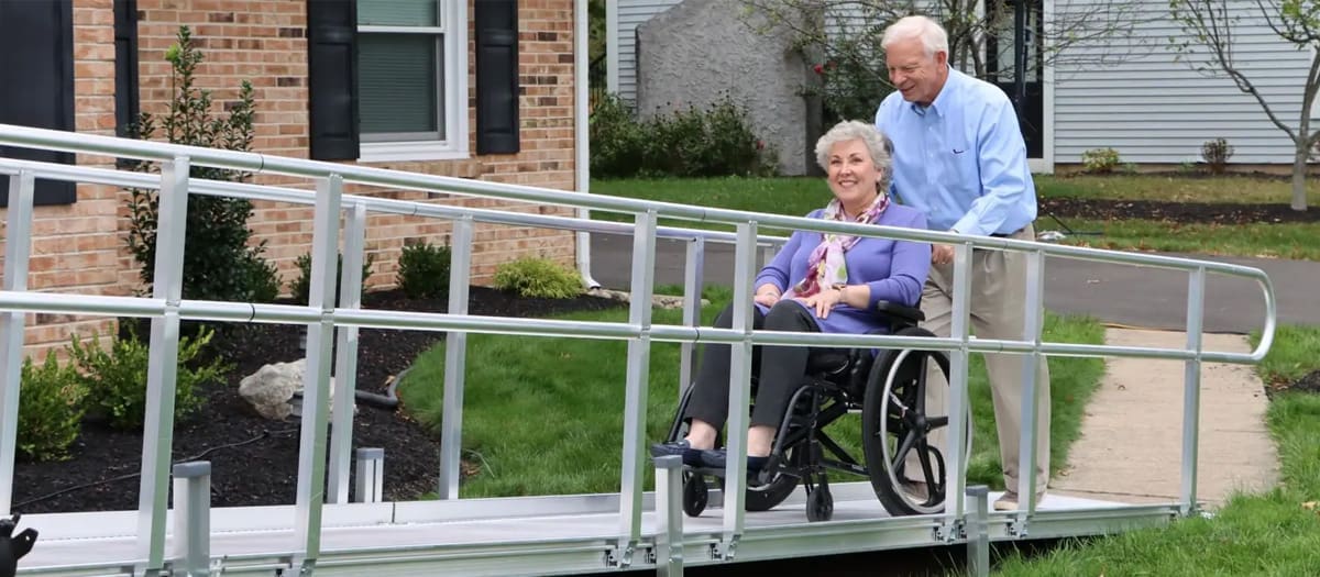 Residential aluminum wheelchair ramp from National Ramps with happy lady in wheelchair being pushed by her husband