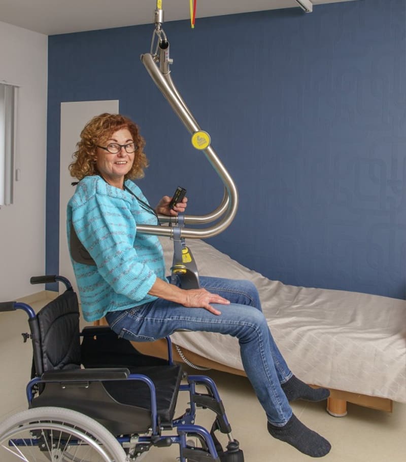 Client transferring independently into wheelchair with ceiling lift and Body Support from SureHands
