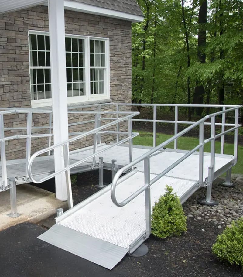 Residential aluminum wheelchair ramp with mesh decking for rain and snow and custom layout to fit owner's house.
